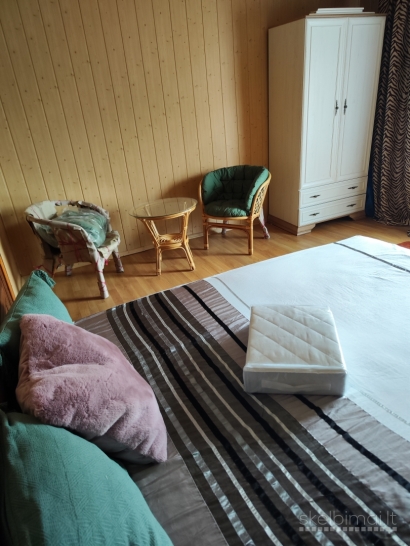 Namas tarp medžių ir miesto šviesų