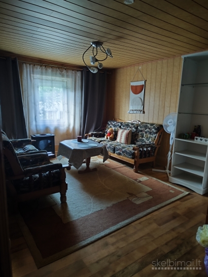 Namas tarp medžių ir miesto šviesų