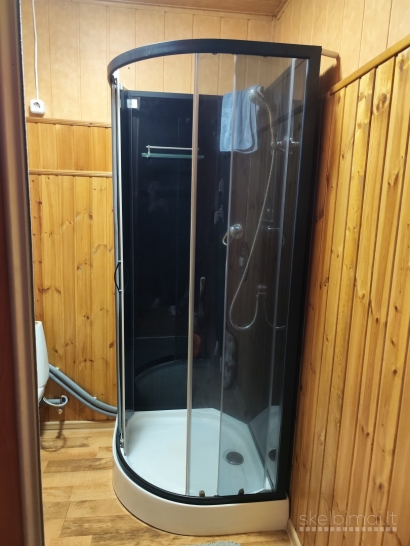 Namas tarp medžių ir miesto šviesų