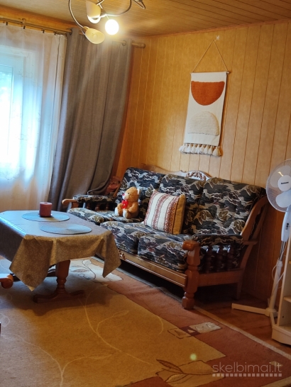 Namas tarp medžių ir miesto šviesų