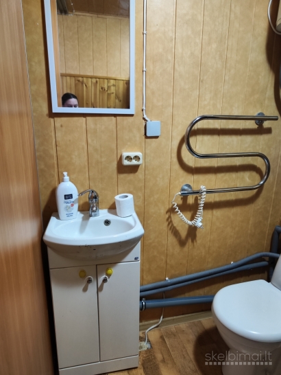 Namas tarp medžių ir miesto šviesų