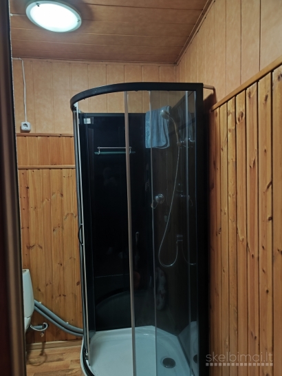 Namas tarp medžių ir miesto šviesų