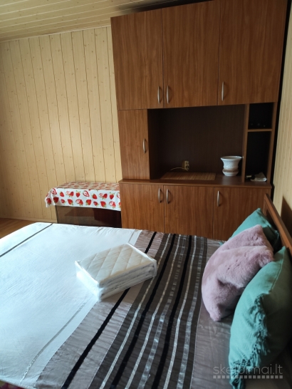 Namas tarp medžių ir miesto šviesų